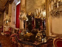 Two elegant chandeliers on a black table in front of a golden mirror