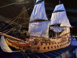A scale model of a ship with white sails