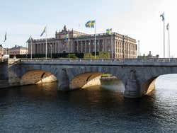 A bridge lined with the Swedish flag, the Swedish parliament building in the distance